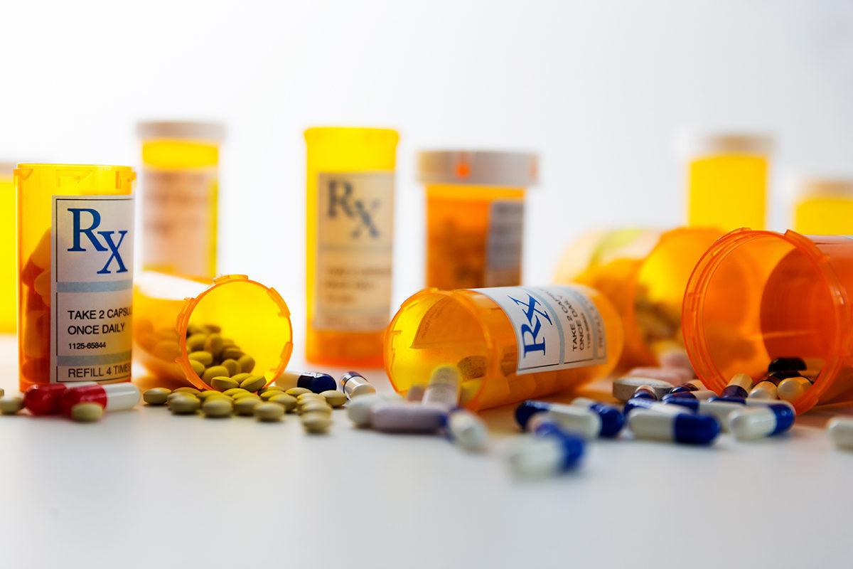 Photo of prescription drug bottles with pills on the ground around them.