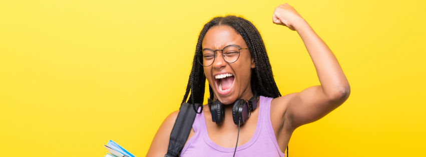 A Black college student pumps her fist in excitement.