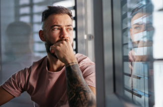 A man sitting near a window, contemplating while looking outside