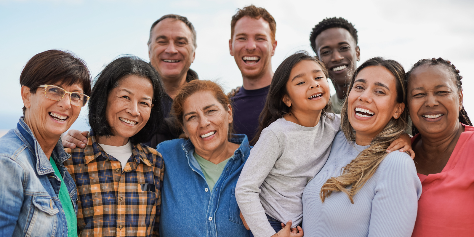 A diverse group of community members, both young and old, smiling for the camera.